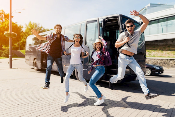 a group of travelrs jump in celebration as they exit their San Diego charter bus